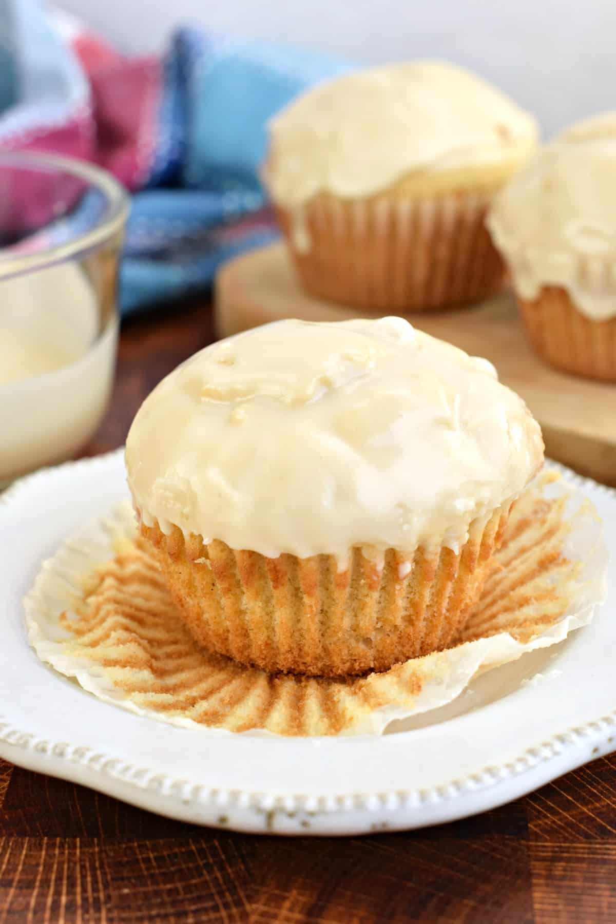 Glazed donut muffin with wrapper peeled off on a white plate.