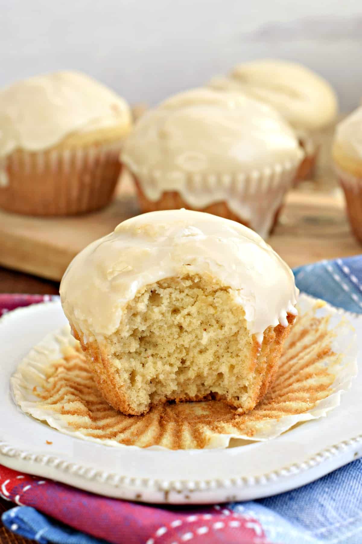 Donut muffin on a white plate with wrapper removed and a bite taken out.