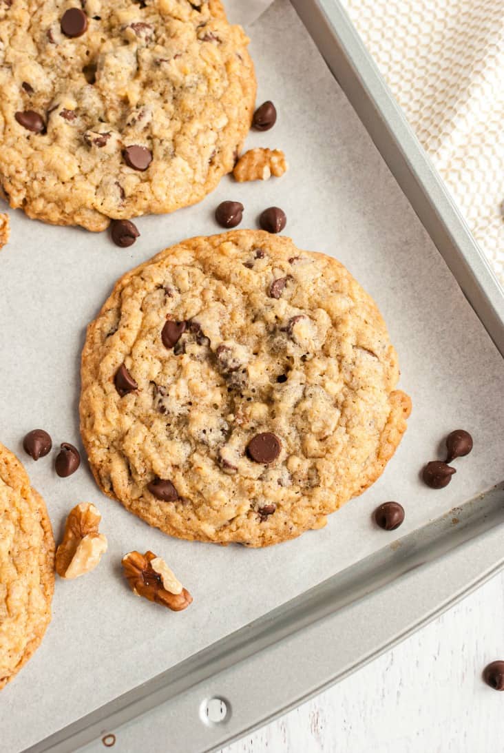 Large chocolate chip cookies baked on a piece of parchment paper lined cookie sheet.