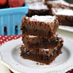 Gooey brownie bars stacked on a white plate.