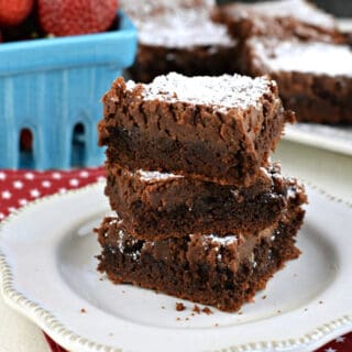 Gooey brownie bars stacked on a white plate.