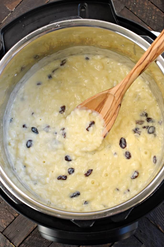 Arroz con leche en la olla a presión con cuchara de madera.