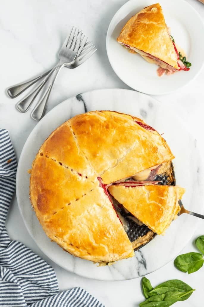 Whole sandwich torte filled with meat, cheese, spinach, and red peppers.