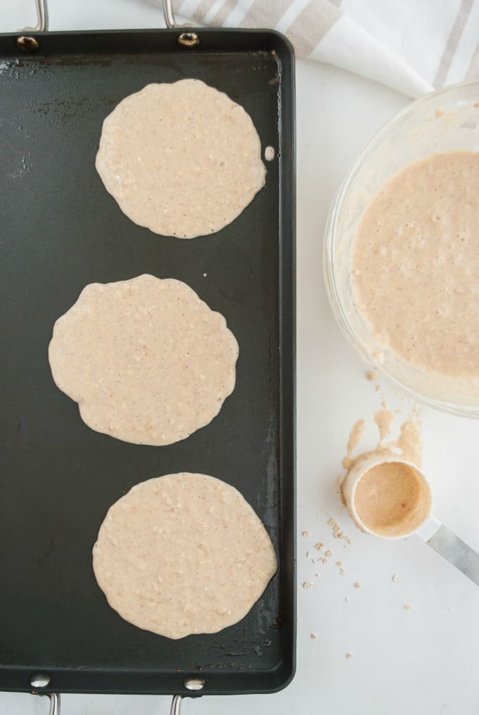 Three pancakes on a hot griddle.