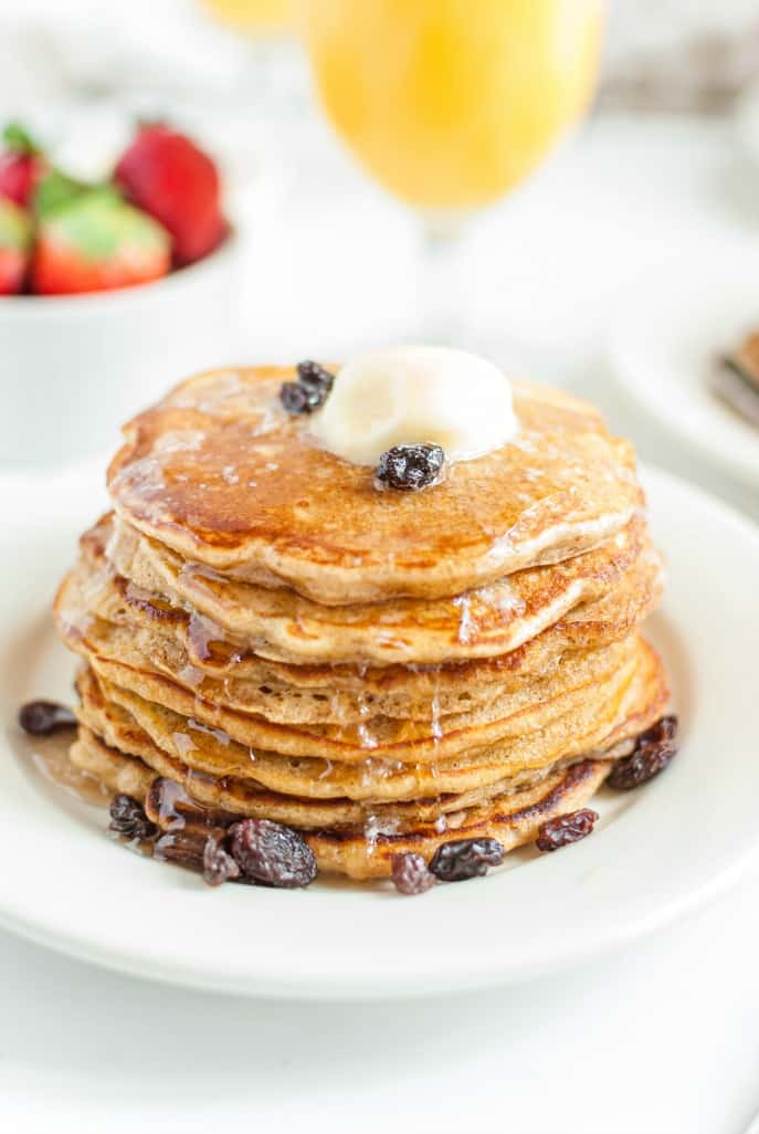 Stack of oatmeal pancakes topped with butter, cinnamon, and raisins!