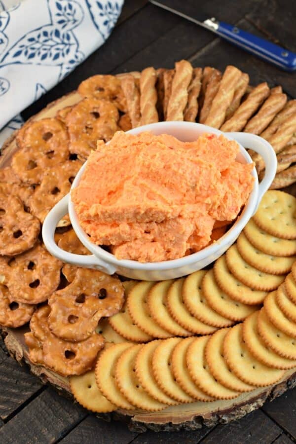Round board with crackers, pretzels, and pimento cheese spread.