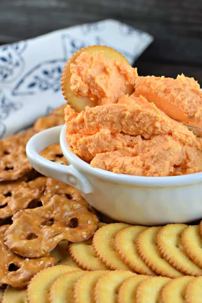 Bowl of pimento cheese dip with a ritz crackers dipped in cheese.