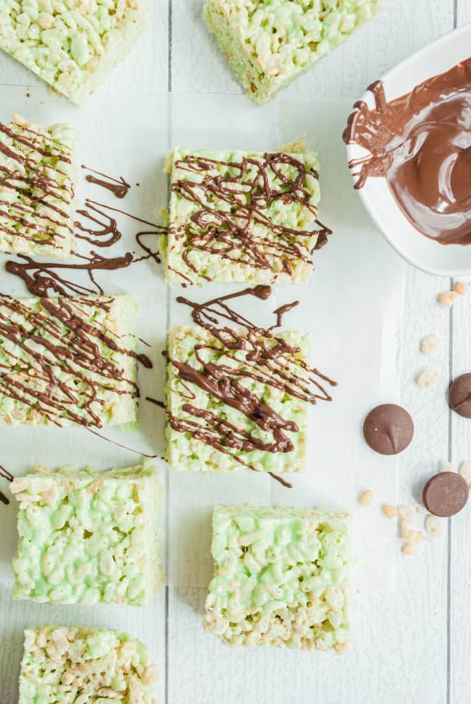 Pistachio Rice Crispy Treats on a white board with dark chocolate drizzle.