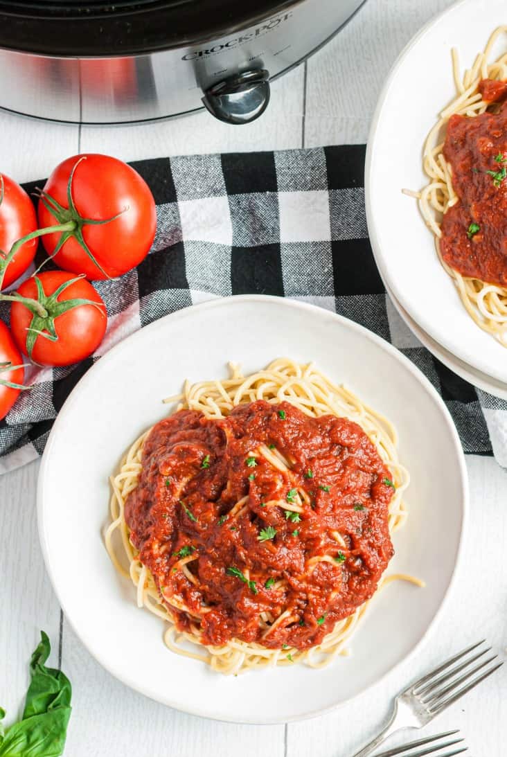 Two white plates with spaghetti noodles topped with homemade marinara sauce.