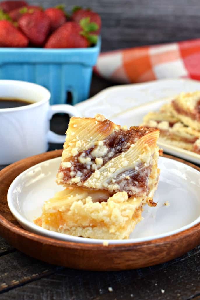 Shortbread bars topped with strawberry preserves and cream cheese crumble on white plate.