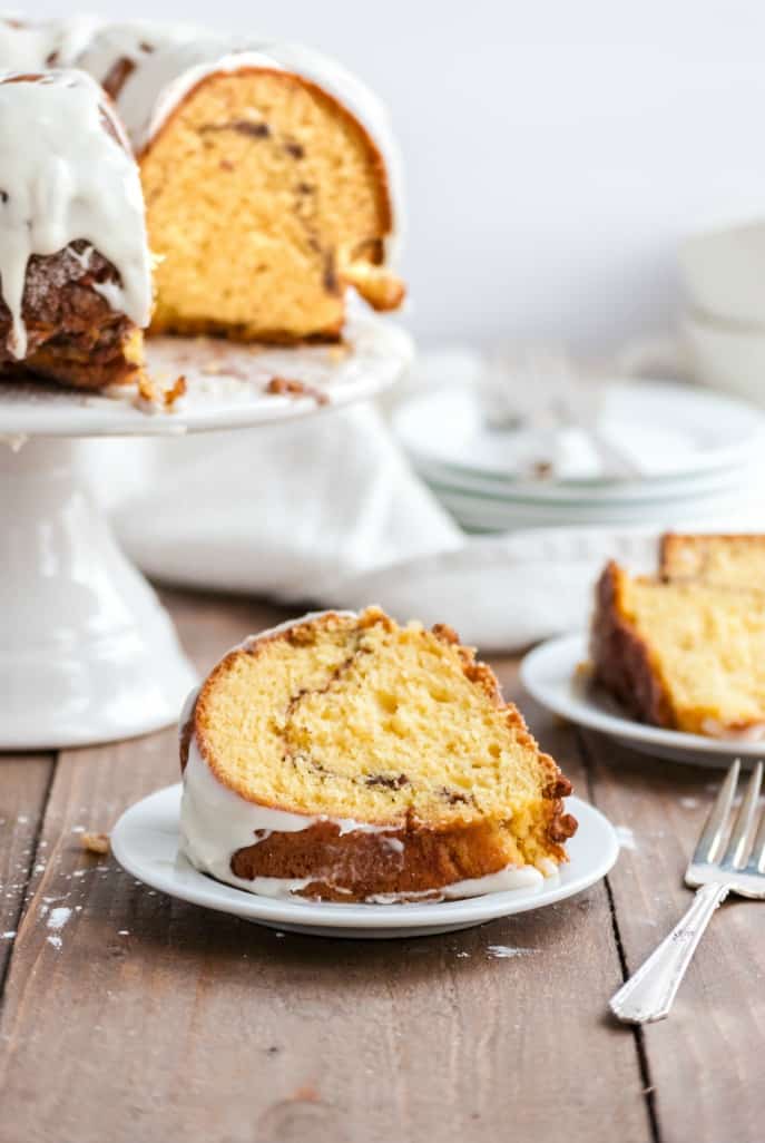 Slice of streusel filling bundt cake on a white plate with wooden table. 