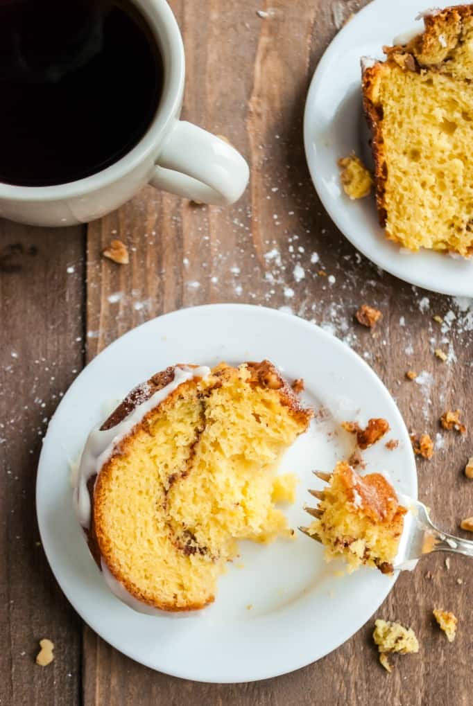 White plate with a slice of cinnamon bundt cake and cup of coffee in a white mug.