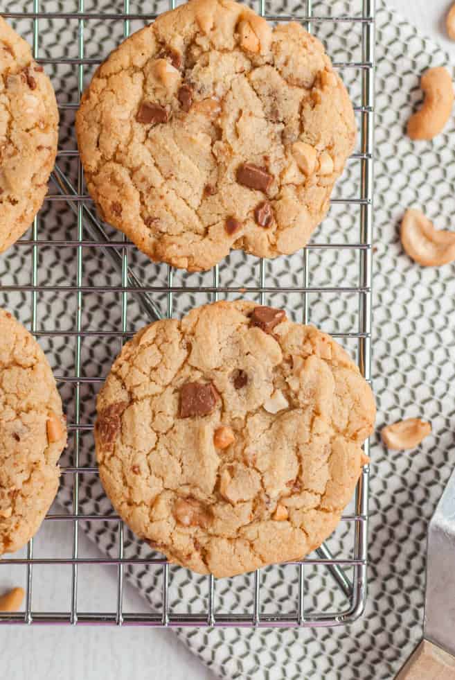 Cookies on a wire rack filled with toffee and cashews.