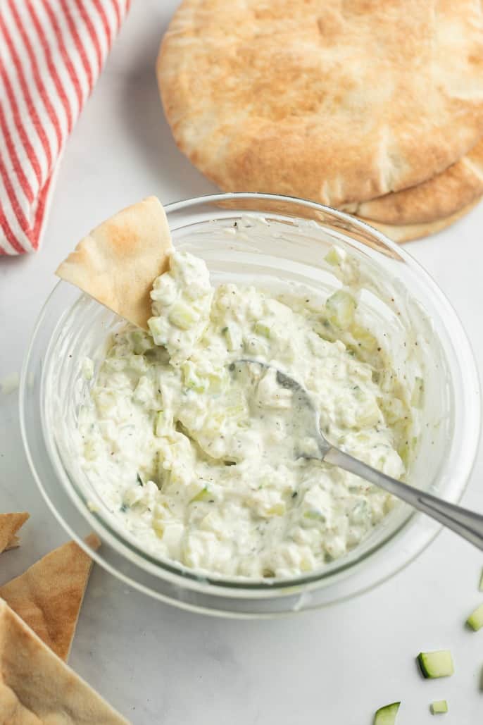 Clear glass bowl with homemade tzatziki sauce and pita bread.