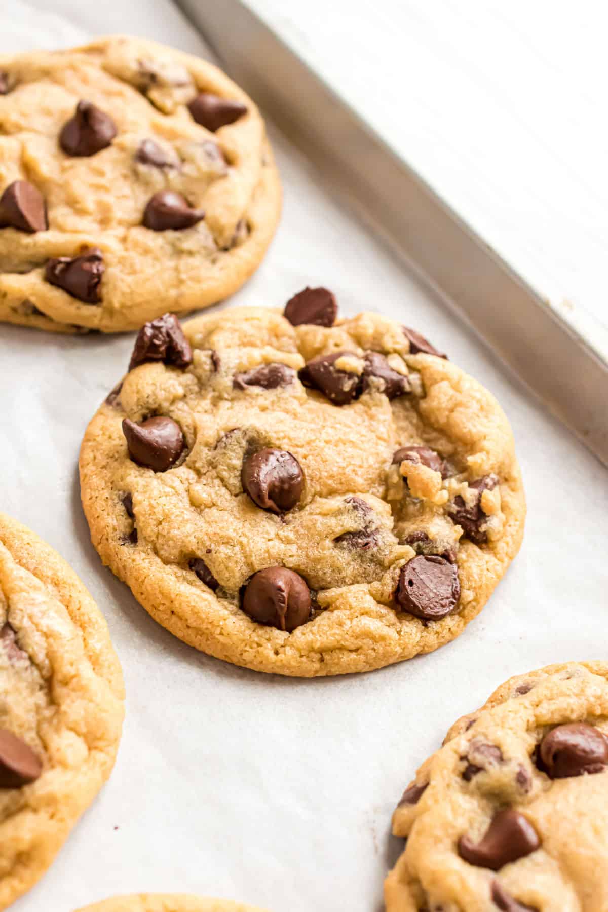 Chocolate chip cookies on baking sheet with parchment paper.
