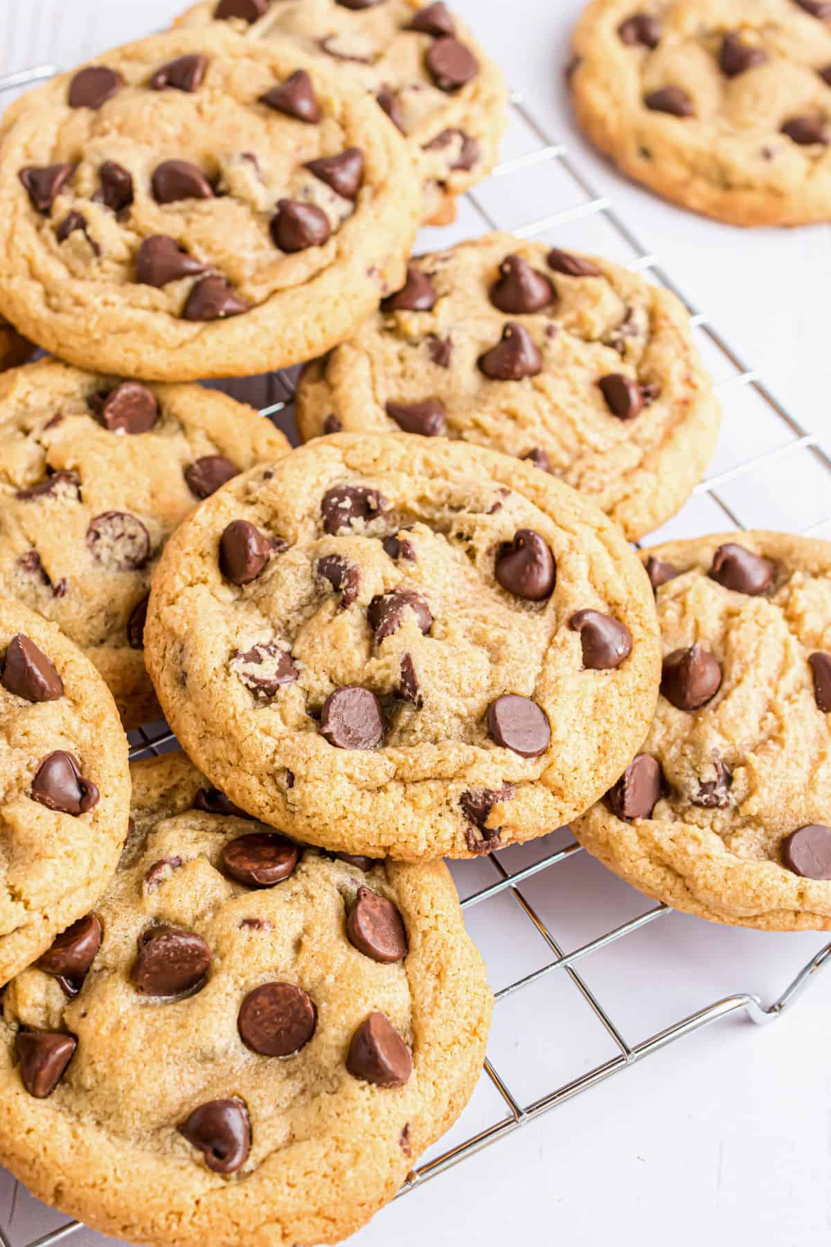 Chocolate chip cookies stacked on a wire rack.