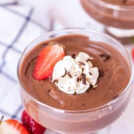 Chocolate pudding in a glass serving bowl with whipped cream, strawberries, and chocolate shavings.