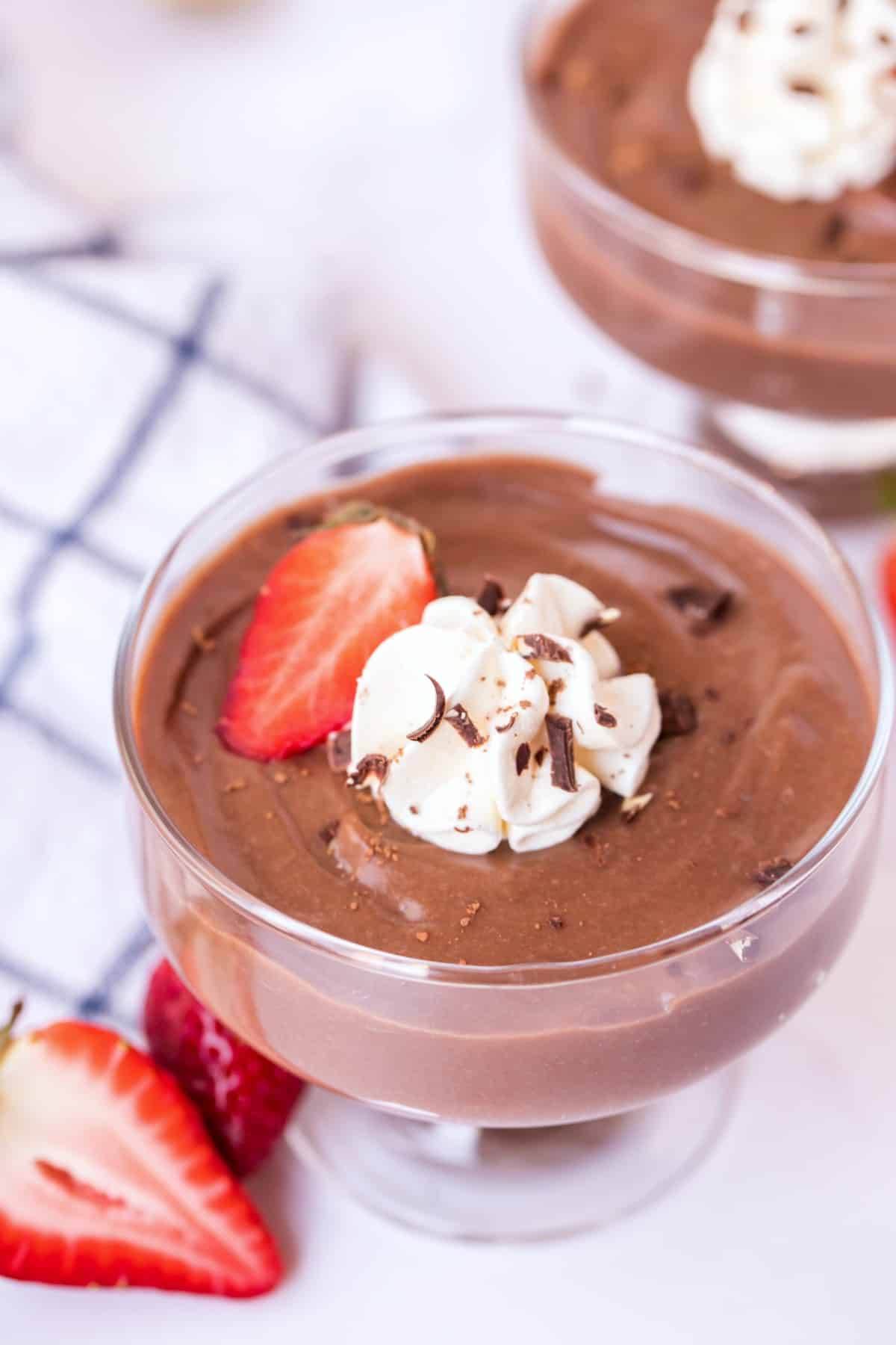 Chocolate pudding in a glass serving bowl with whipped cream, strawberries, and chocolate shavings.