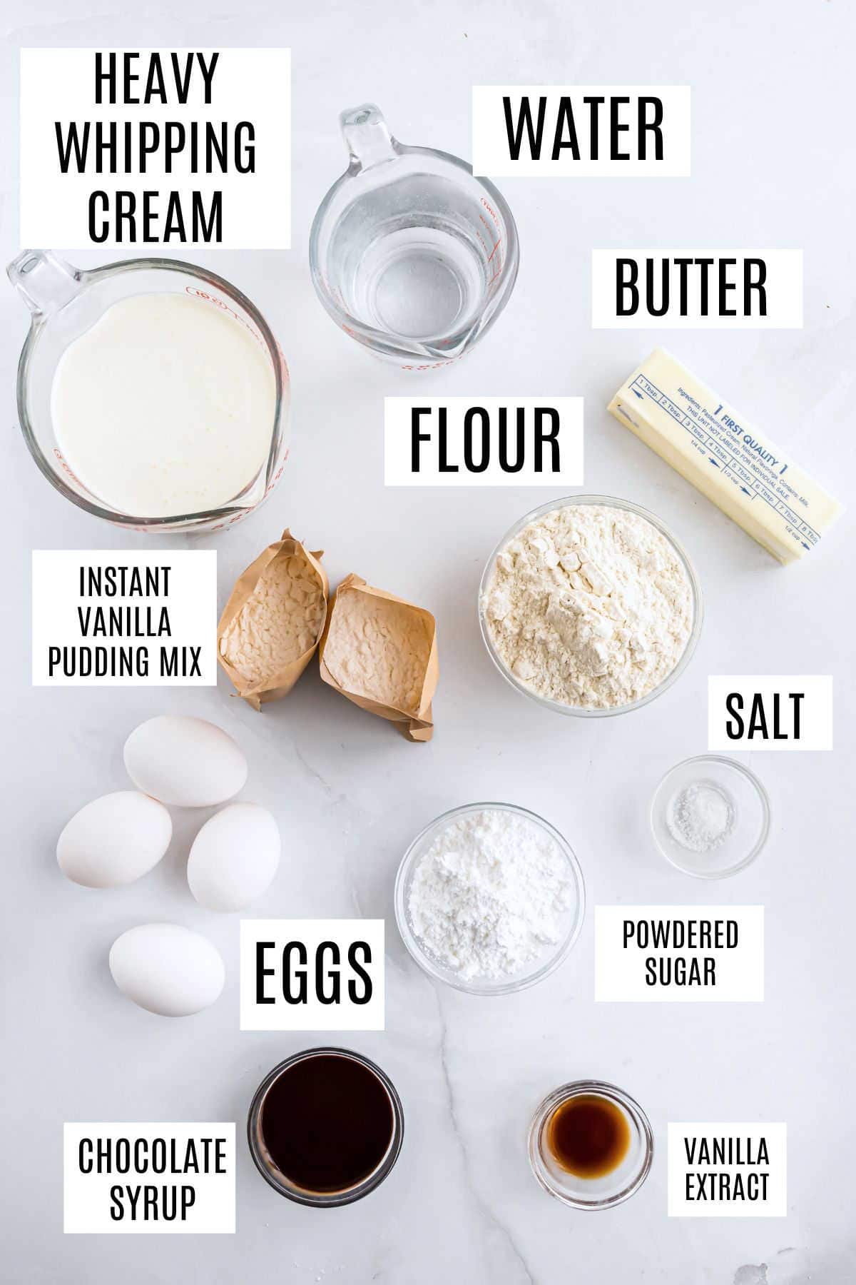 Ingredients for a cream puff dessert on a white surface: cream, water, butter, flour, eggs, sugar, syrup, pudding mix, salt, vanilla.
