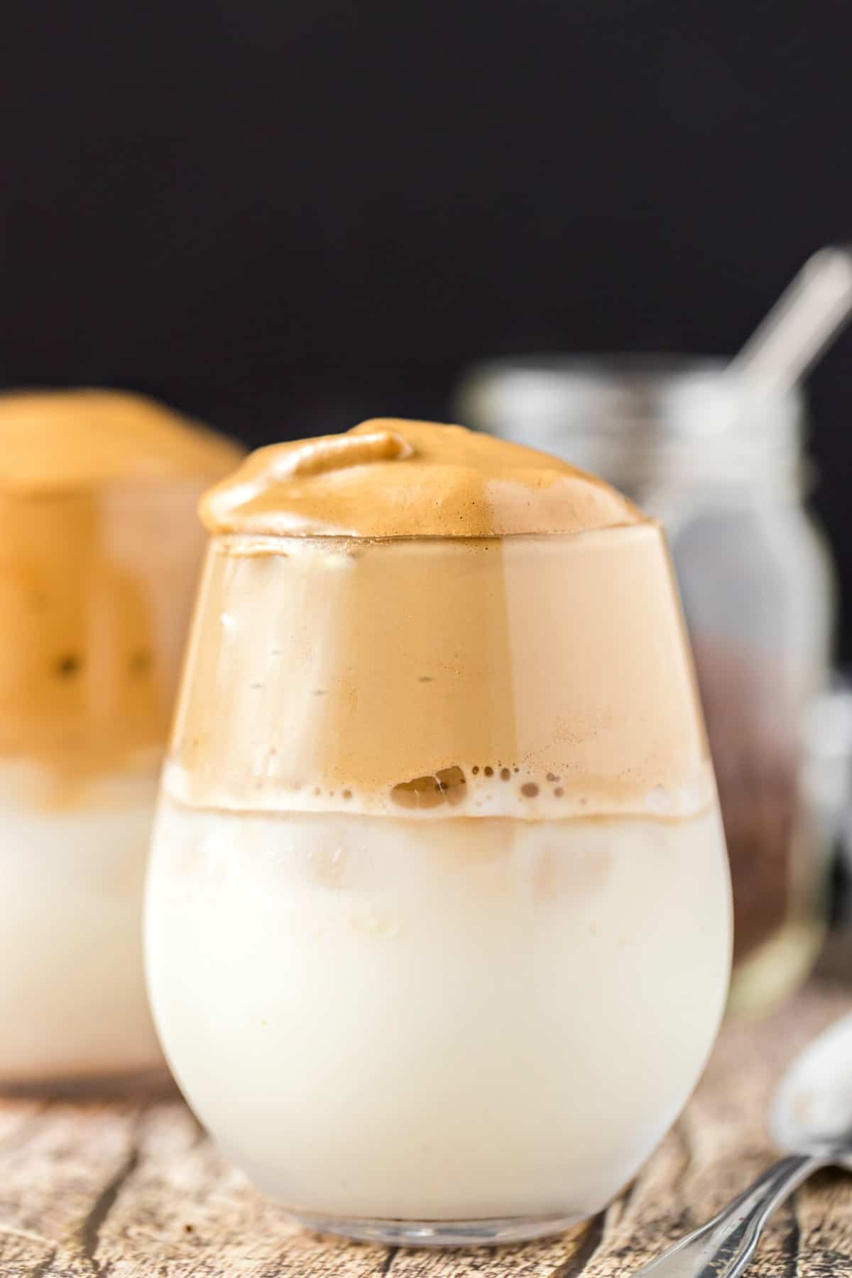 Clear stemless wine glass with whipped coffee over milk.