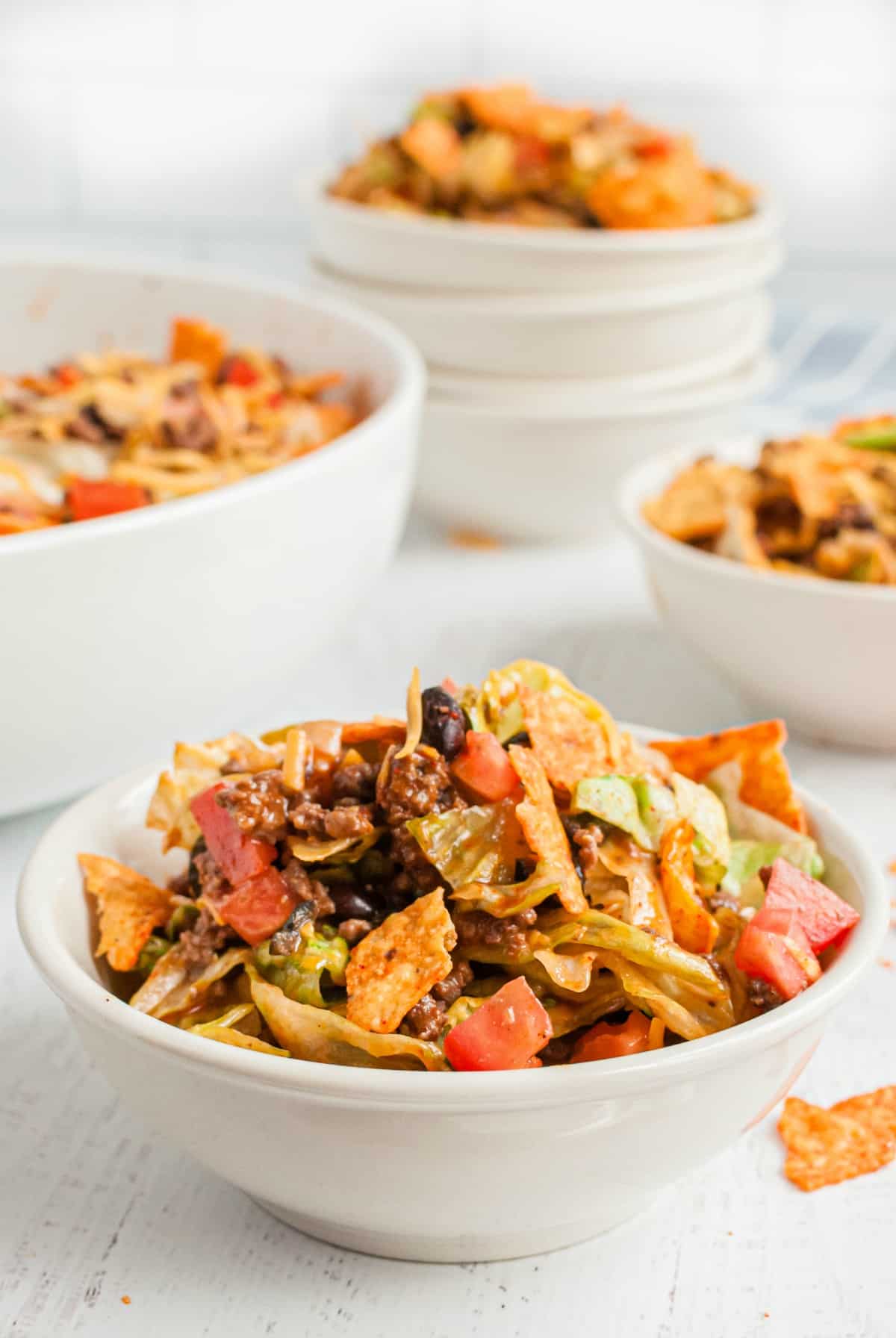 Taco salad in white dinner bowls topped with doritos.