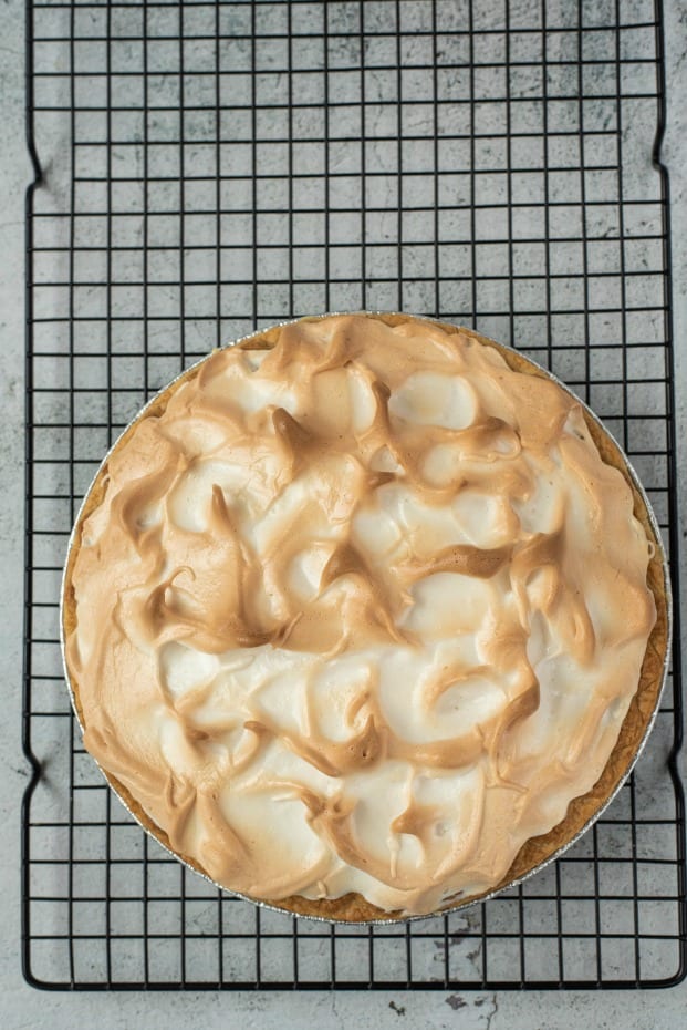 Baked lemon meringue pie on a wire rack to cool.