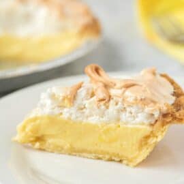 Slice of lemon meringue pie on a white plate.