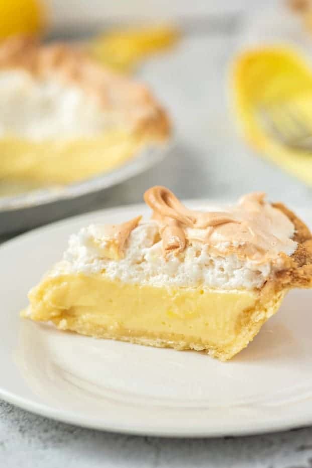 Slice of lemon meringue pie on a white plate.