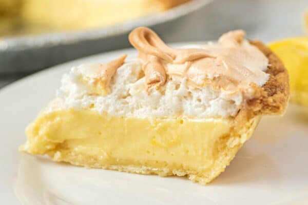 Slice of lemon meringue pie on a white dessert plate.