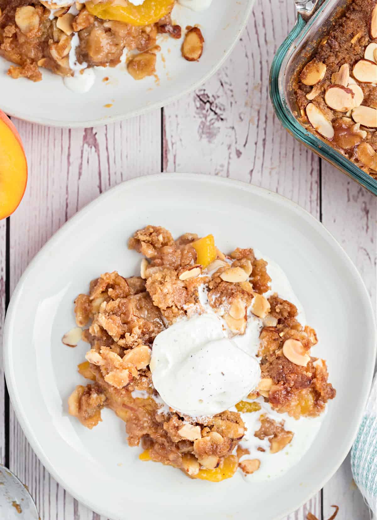 Peach crisp on a plate with melted vanilla ice cream on top.