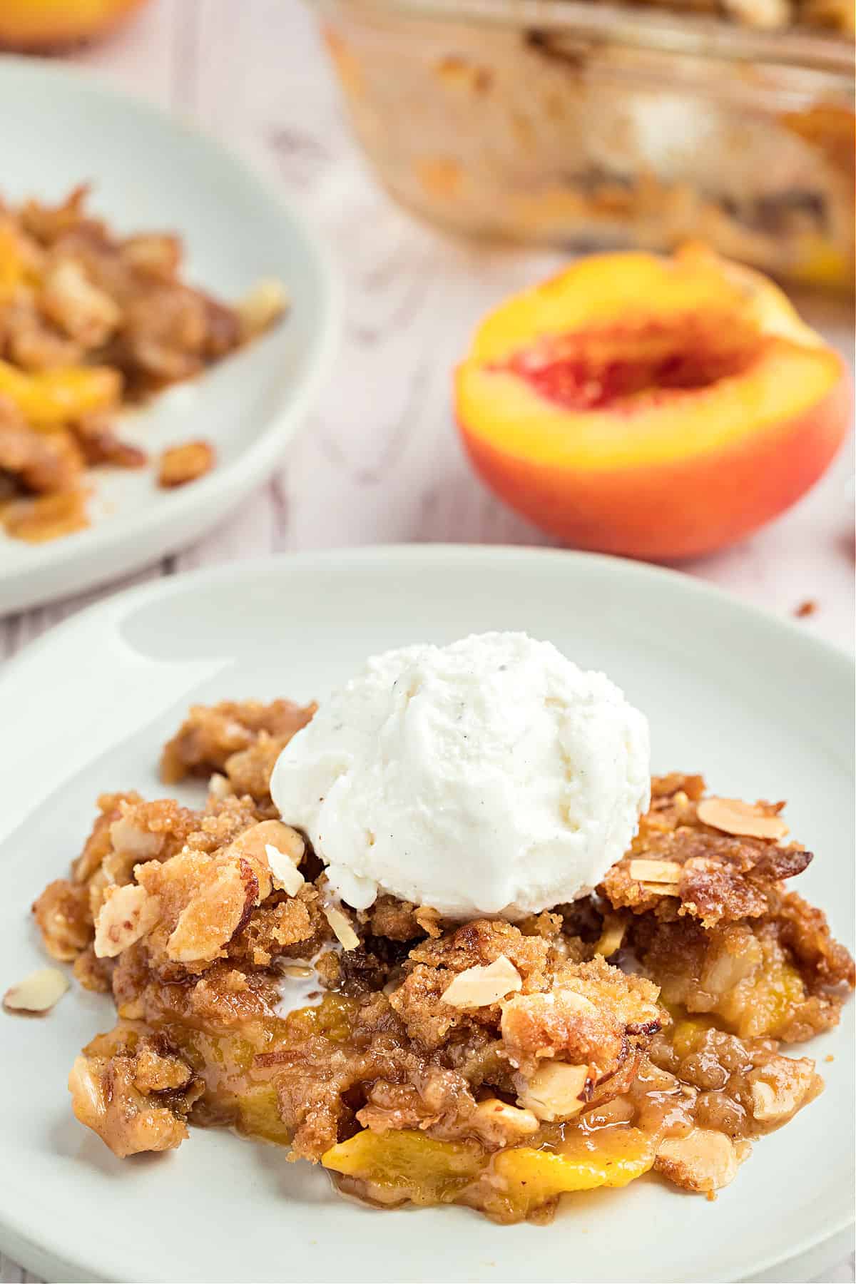 Peach crisp on a plate with a scoop of vanilla ice cream.