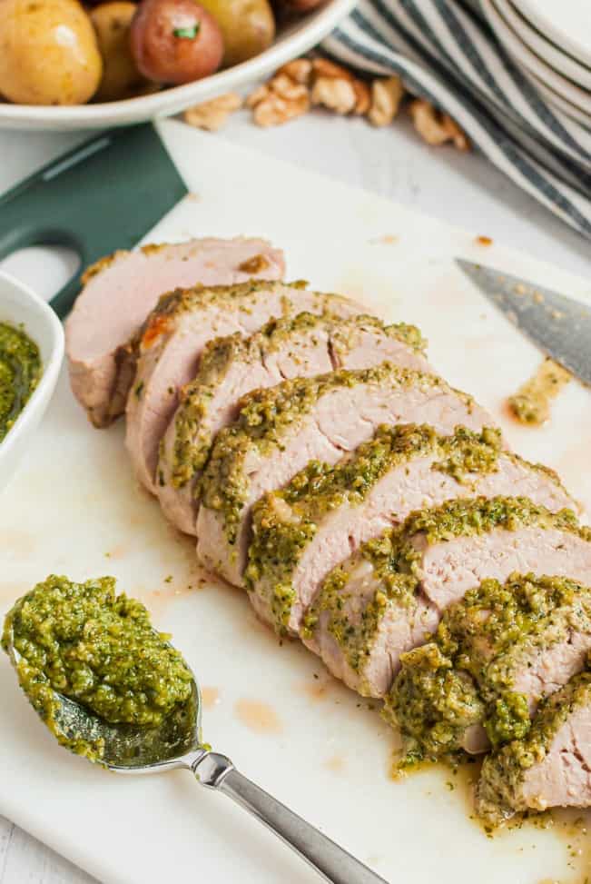 Thick walnut pesto glazed on top of a sliced pork tenderloin after cooking and ready to serve.