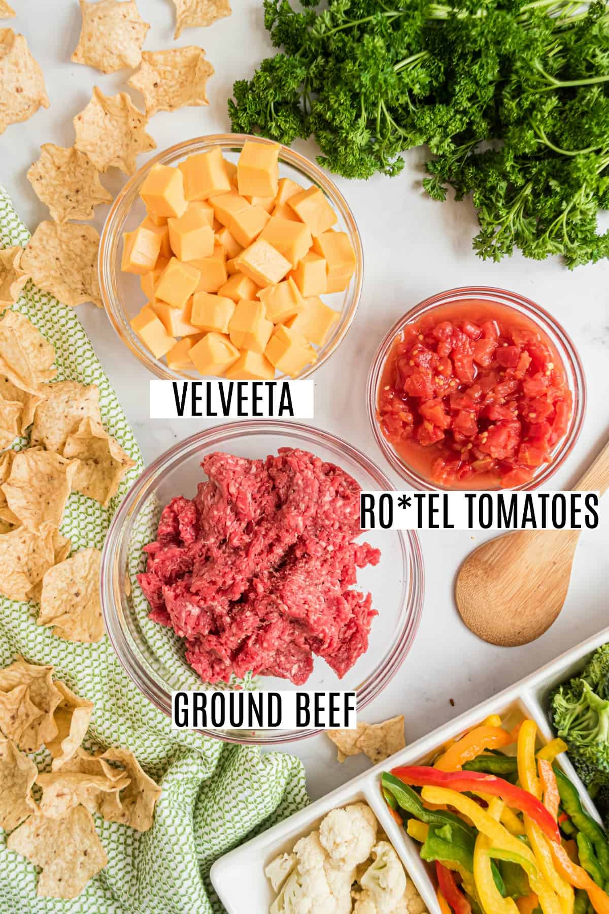 Three ingredients needed to make rotel dip, including ground beef, velveeta cheese, and rotel tomatoes.