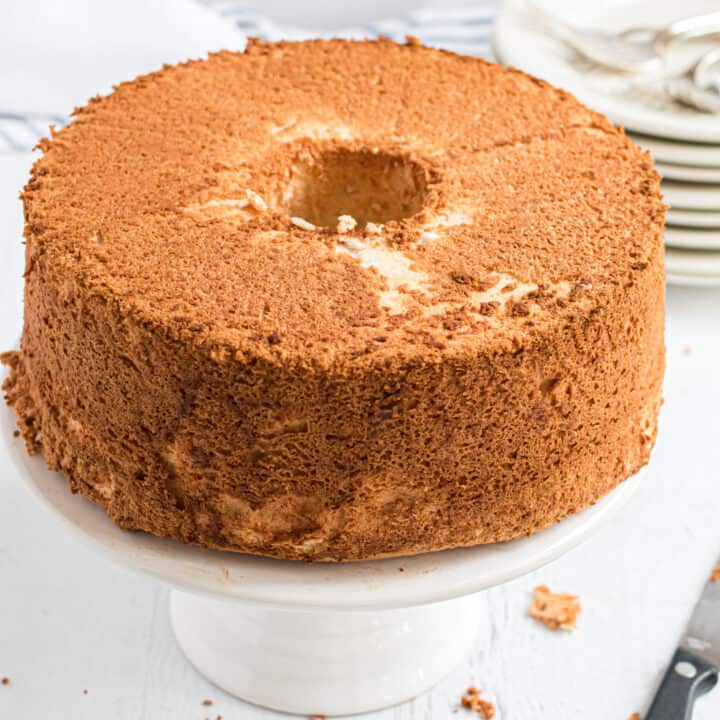 Angel Food cake on a white cake platter with sharp knife next to the cake.