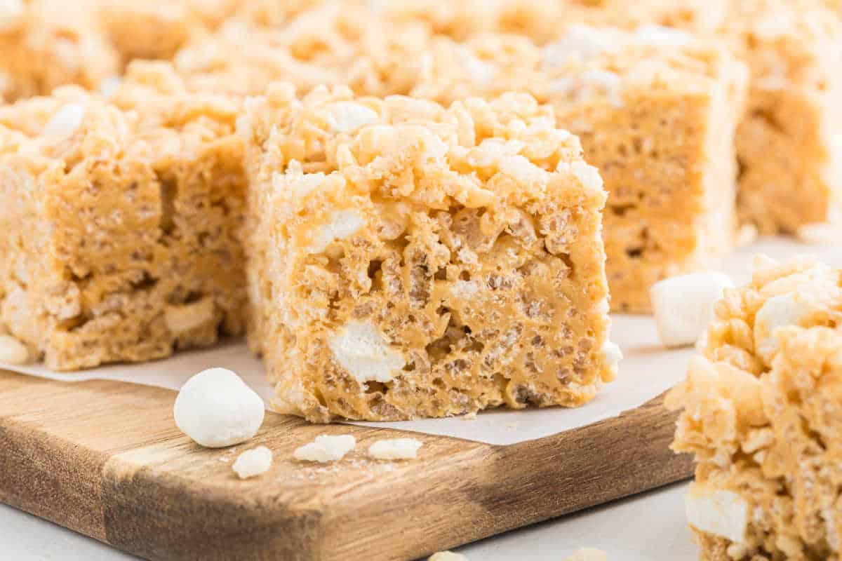 Close-up of Biscoff Rice Krispie Treats with peanut butter and mini marshmallows on a wooden board.