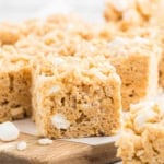 Close-up of Biscoff Rice Krispie Treats with visible marshmallows, cut into squares and placed on a wooden board.
