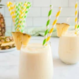 Copycat disney dole whip in a stemless wineglass garnished with a pineapple slice.