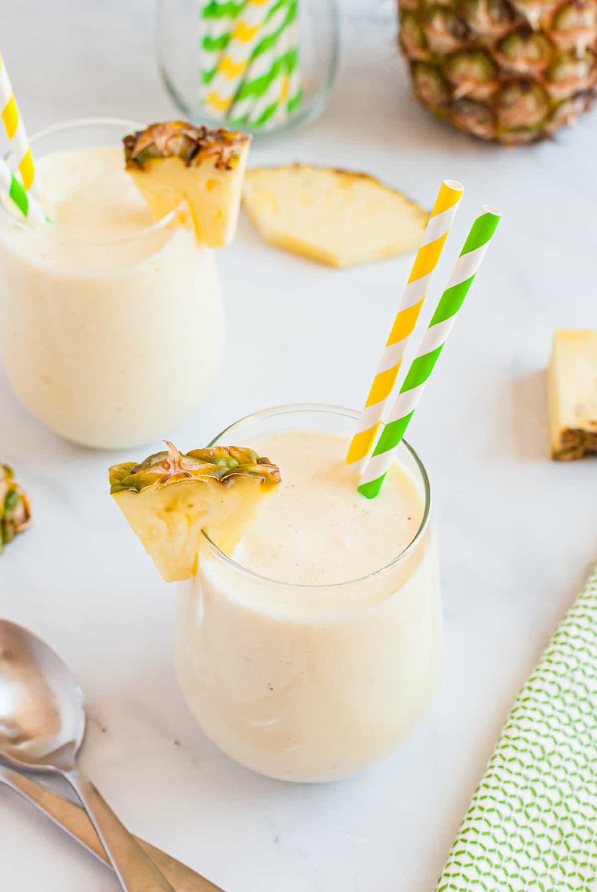 Overhead view of dole whip in wine glasses with pineapple,ice cream, and straws.