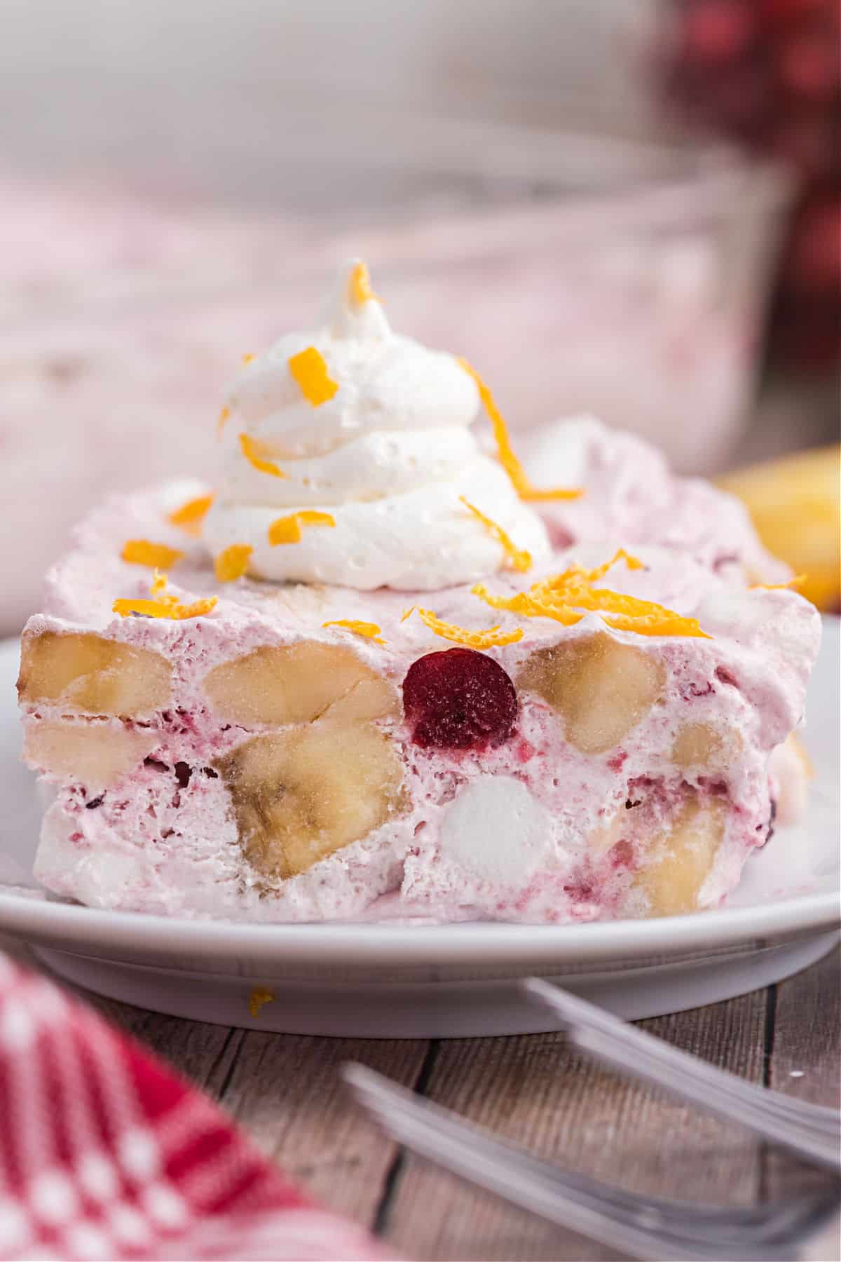 Slice of frosty cranberry salad topped with whipped cream and orange zest.