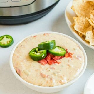 Queso in a white bowl with instant pot in background. Served with tortilla chips.