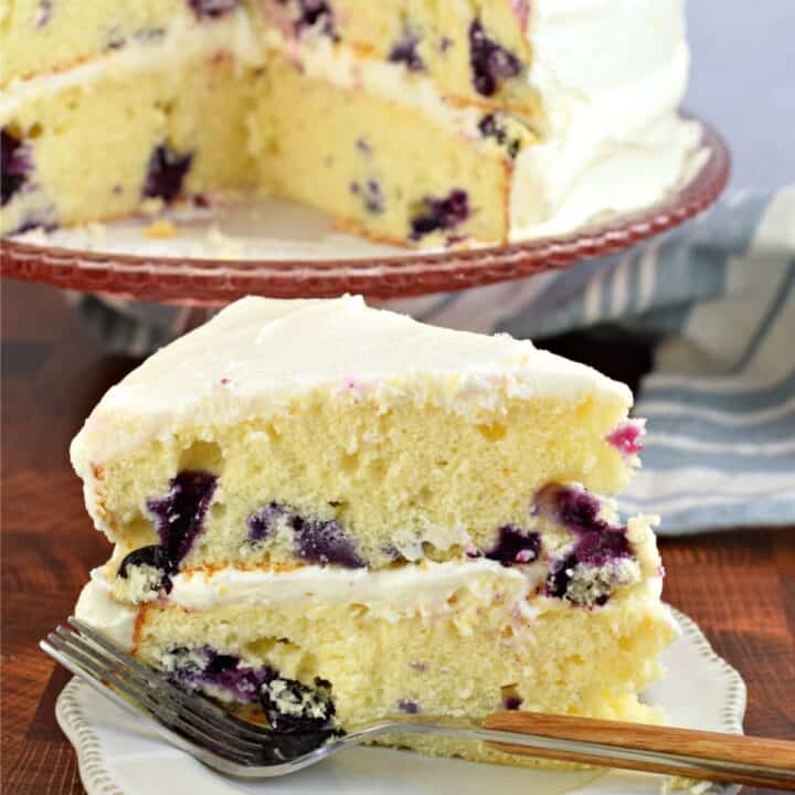 Lemon blueberry cake on a white dessert plate with fork.