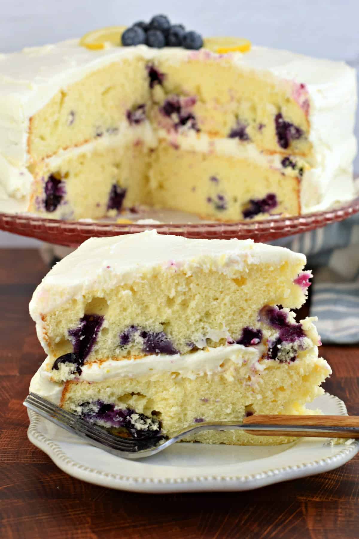 Slice of cake with lemon and blueberry on a white plate with fork.