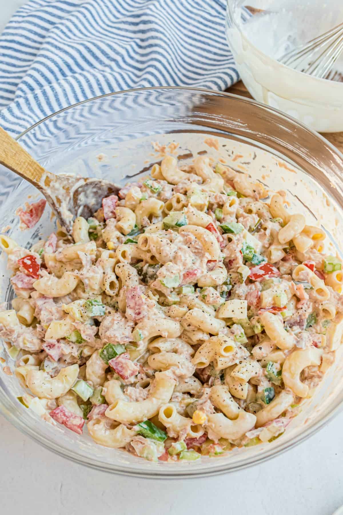 Macaroni salad in a clear glass bowl with tuna, eggs, and creamy dressing.