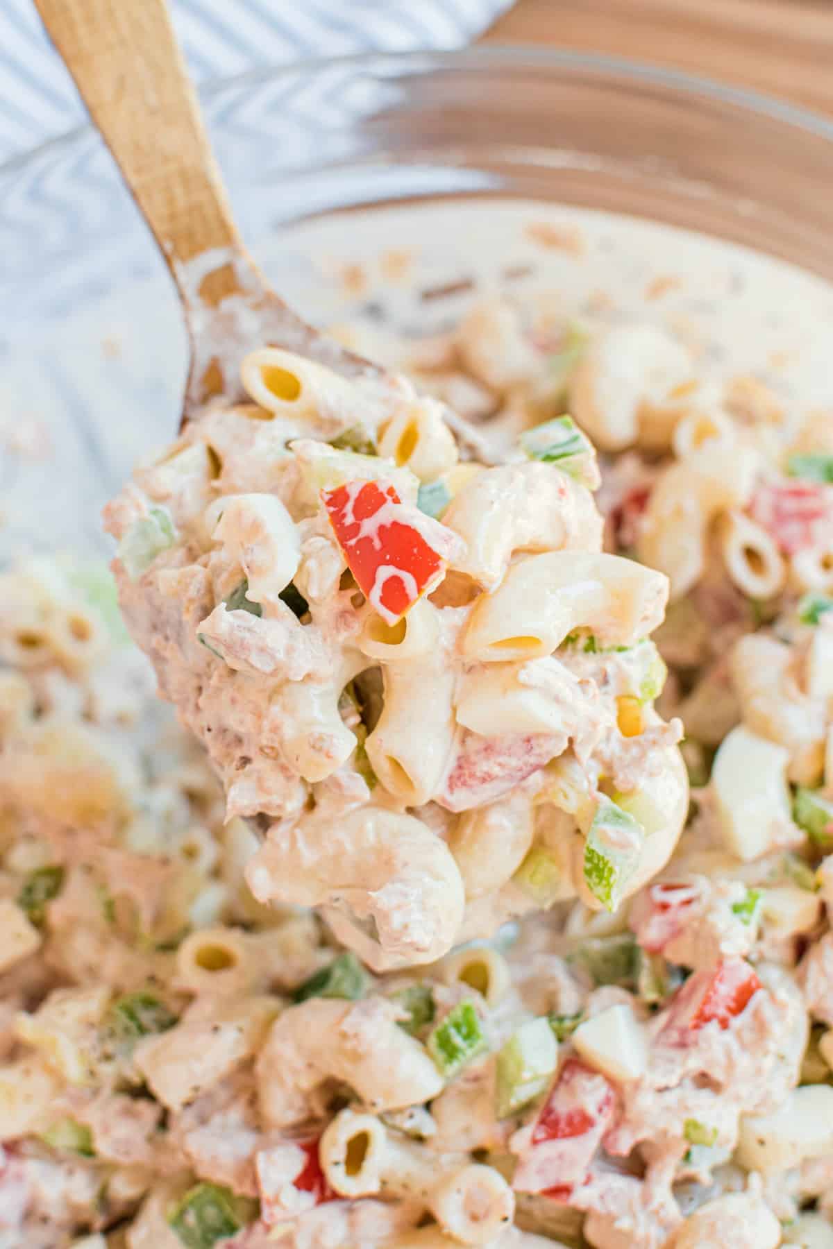 Macaroni salad scooped on a wooden spoon.