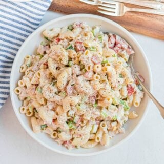 Macaroni salad with vegetables, tuna, eggs, and creamy dressing in a white bowl to serve.