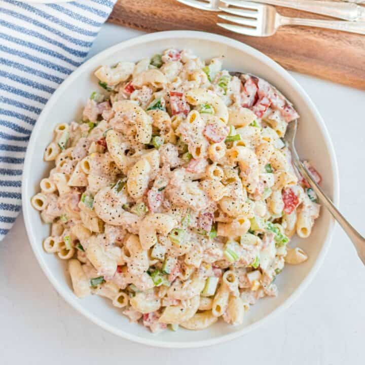 Macaroni salad with vegetables, tuna, eggs, and creamy dressing in a white bowl to serve.