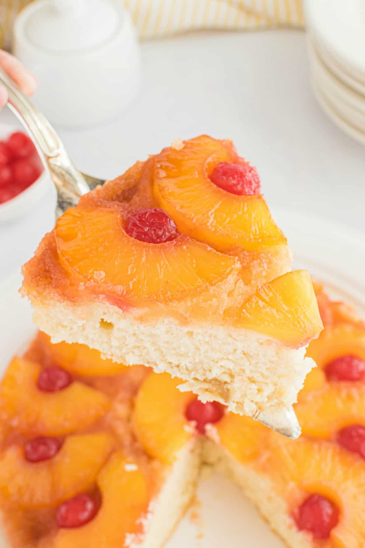 Slice of pineapple upside down cake being lifted out of cake pan with a pie server.