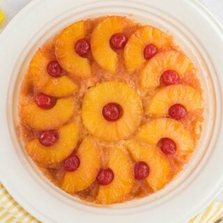 Pineapple upside down cake on a white cake plate.