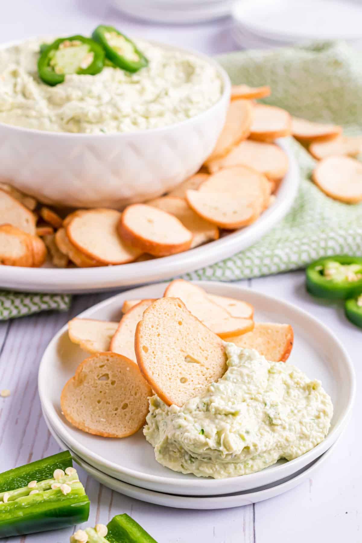 Artichoke jalapeno dip served on a plate with bagel chips.