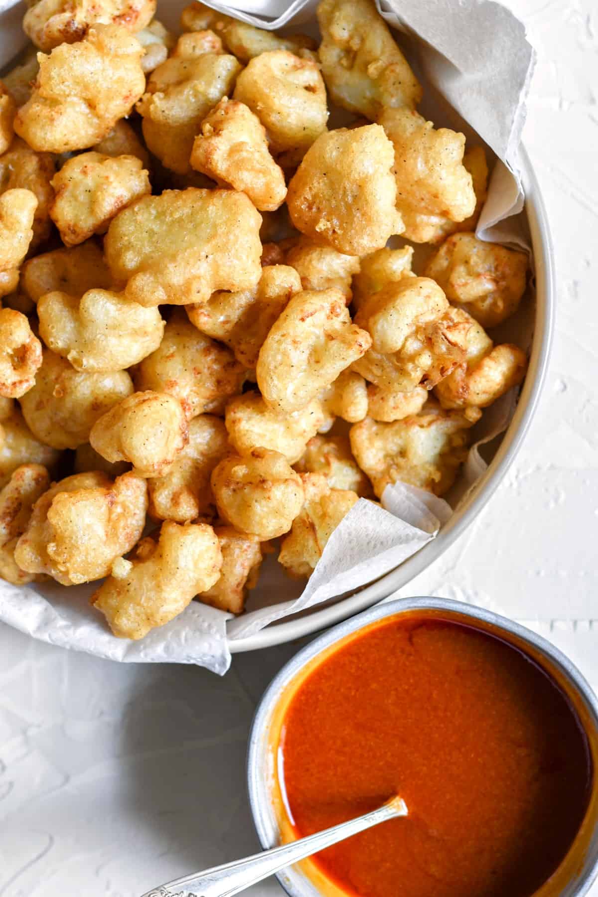 Pan fried cauliflower wings with a bowl of homemade buffalo sauce.